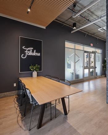A conference room with a wooden table and chairs, a sign that says